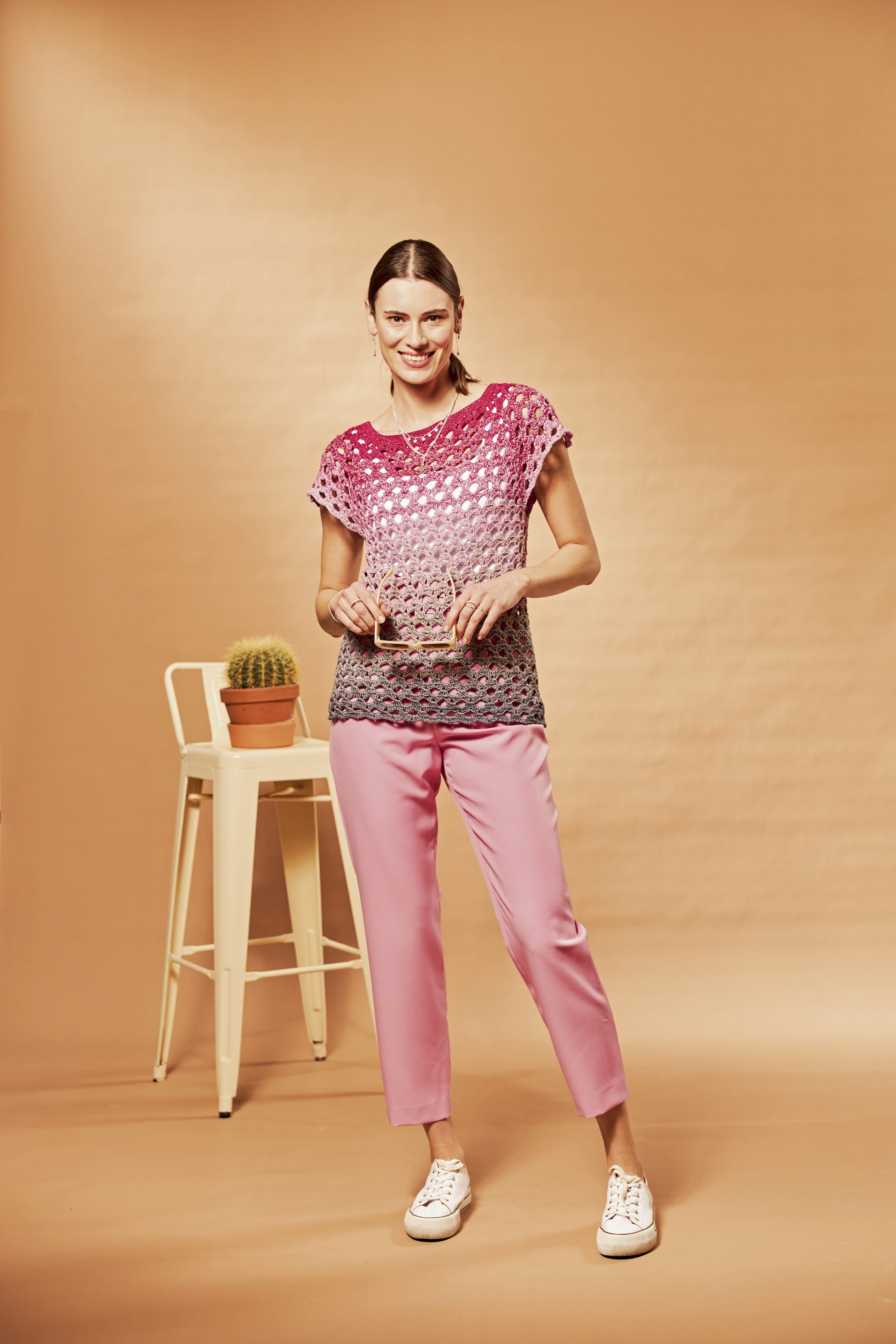 Modische, handgemachte Häkelbluse in Ombré, kombinierbar mit pastellrosafarbener Hose. Lässig und stilvoll.