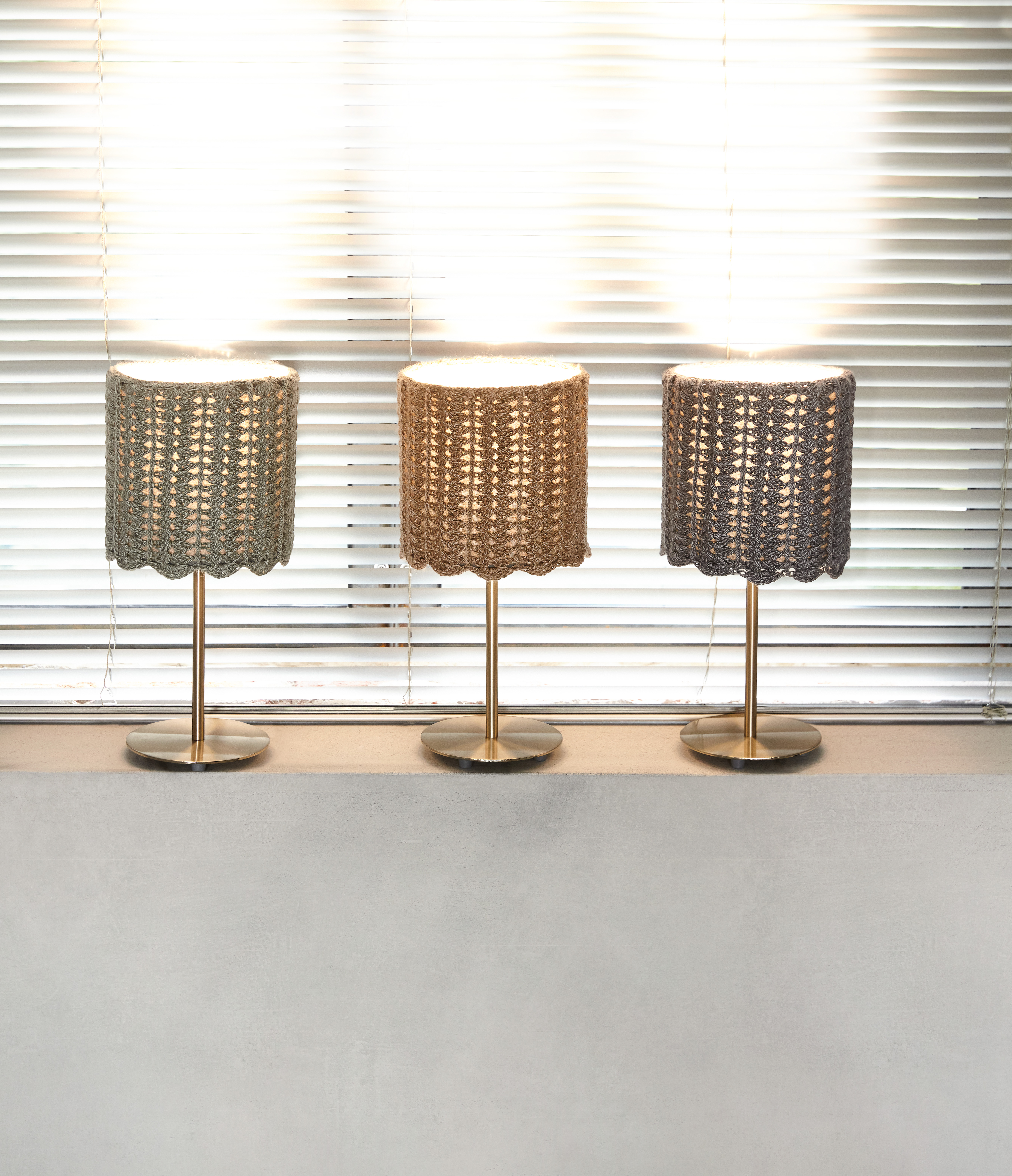 Modische Häkel-Lampenschirme in sanften Farbtönen. Handarbeit, elegante Wellenmuster, edle Messing-Ständer.