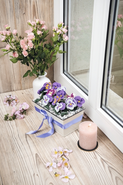 Handgemachte violette Blumen in geflochtener Schachtel mit Schleife, zarte Akzente, DIY-Dekoration.
