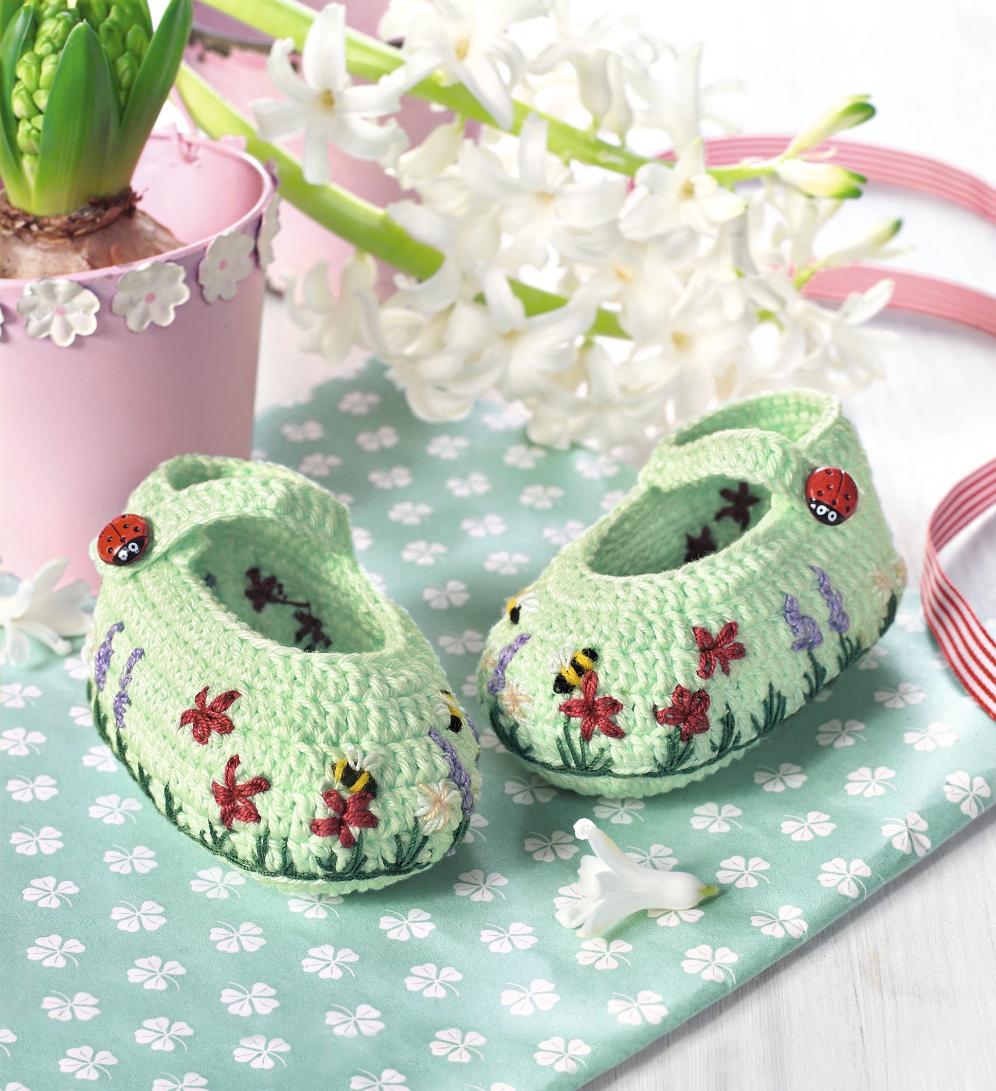 Grüne, gehäkelte Babyschuhe mit Blumenstickerei, verziert mit Marienkäferknöpfen, DIY-Charme, handgefertigt.
