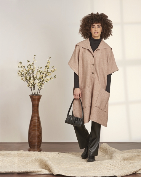 Weit geschnitten, beige Cape mit Knopfleiste; schwarz-klassische Lederhose, Oversize-Taschen; stilvoll, zeitlos.
