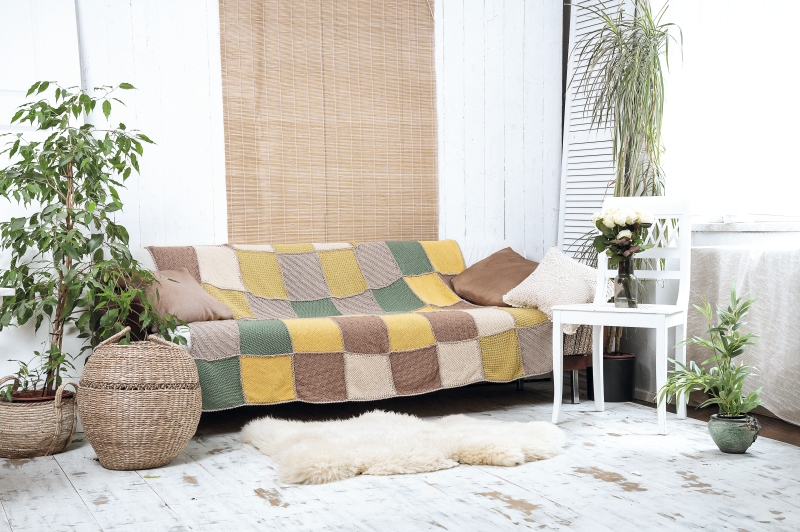 Farbenfroher, handgemachter Patchwork-Überwurf; quadratische Muster in Gelb, Grün, Braun; modisch und gemütlich.