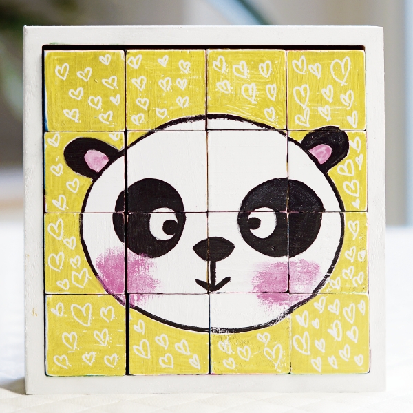 Fliesenbild mit Panda-Motiv, gelbem Hintergrund und Herzmustern. Handgemacht und kreativ gestaltet.