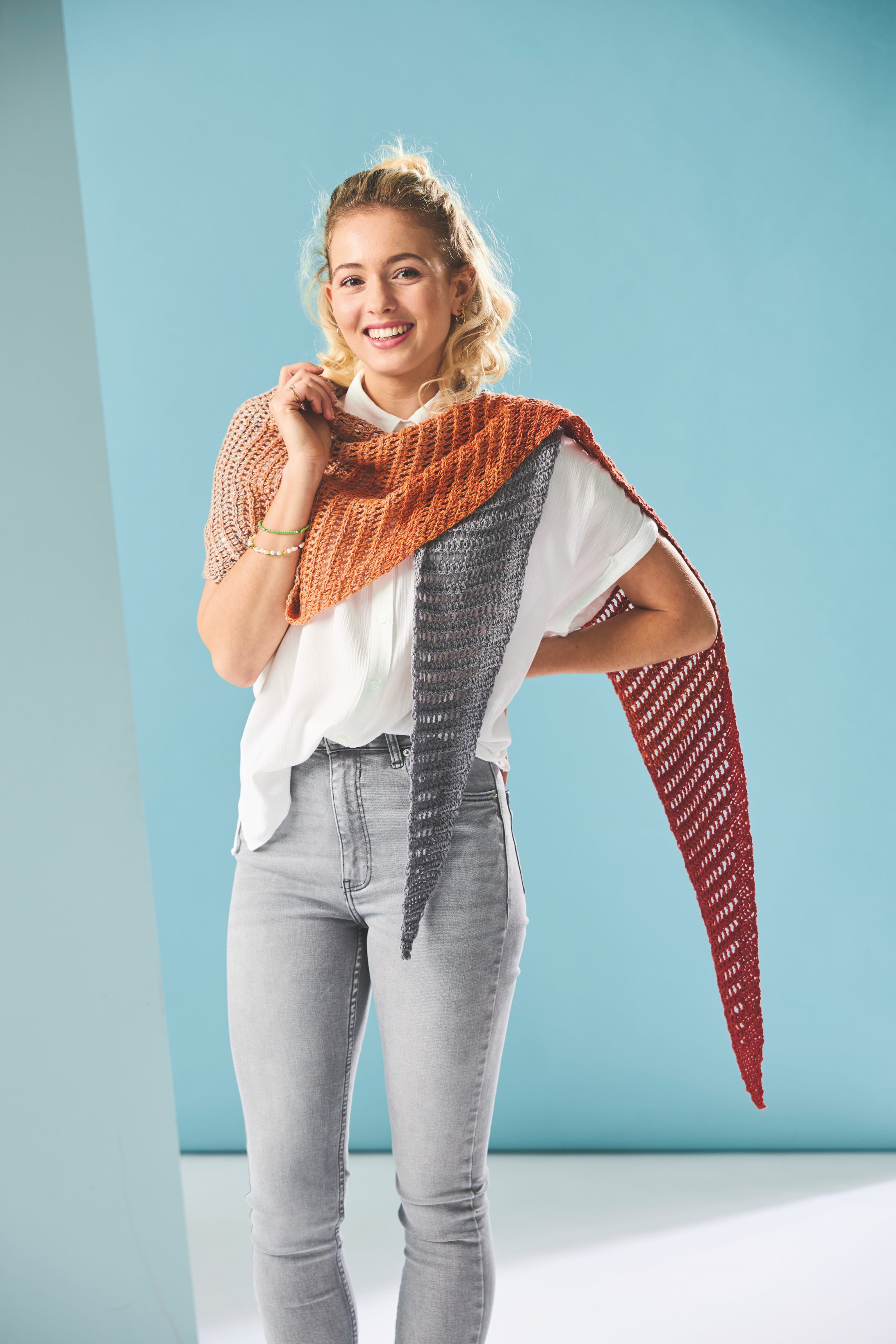 Handgemachtes Triangeltuch in Erdtönen, grobmaschig gestrickt. Modisch lässig über weißer Bluse und hellen Jeans.