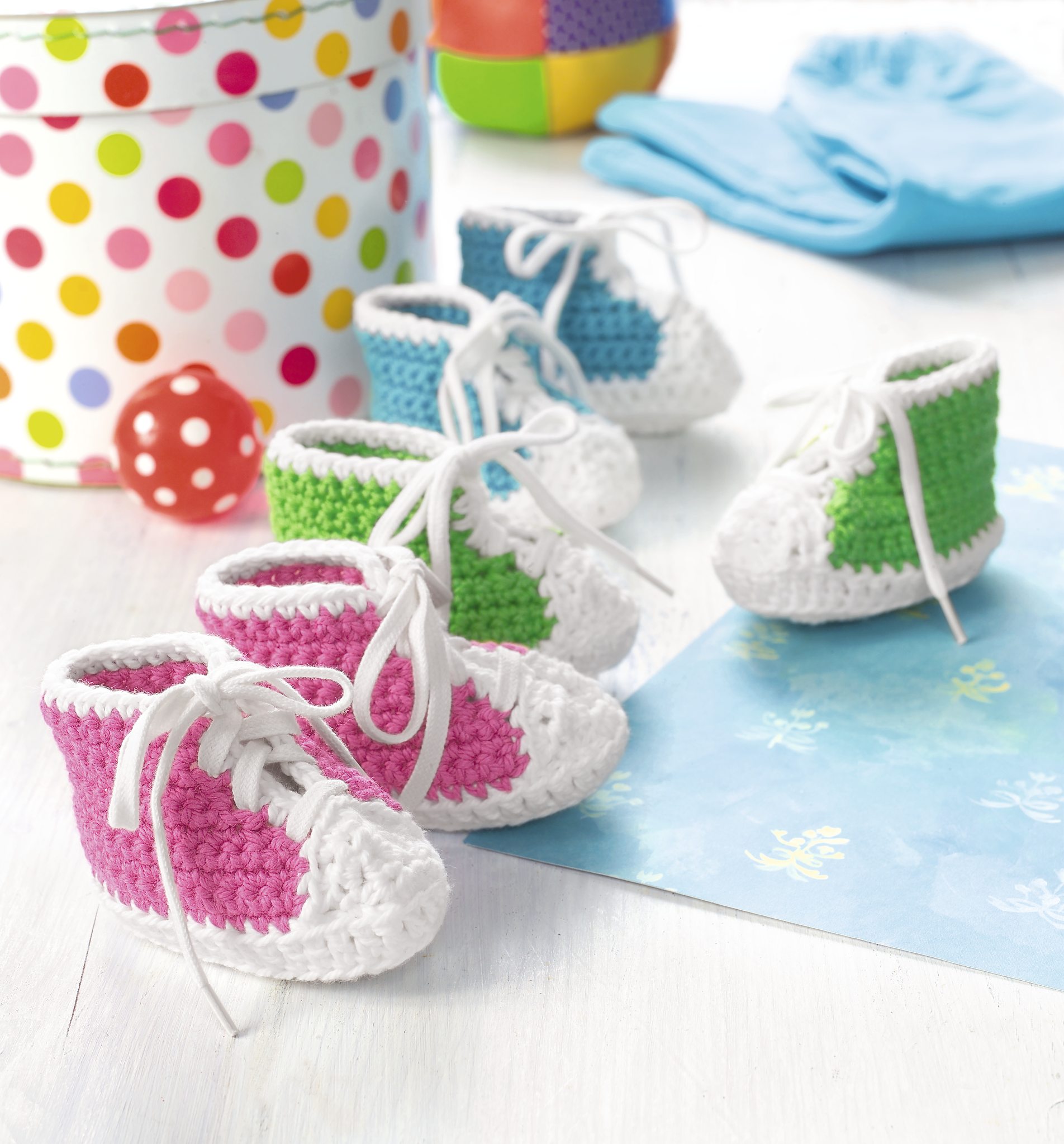 Häkel-Babyschuhe in Rosa, Blau und Grün mit weißen Details. Handgemacht, klassischer Sneaker-Schnitt, modisch DIY.