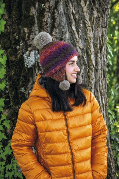 Farbige, handgestrickte Mütze mit Bommel, gestreift. Orange Steppjacke, modern geschnitten.