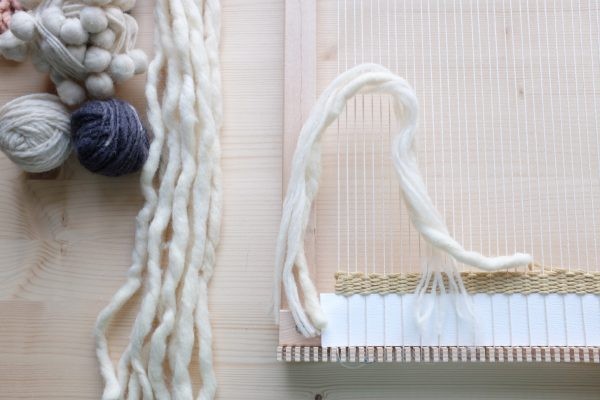 Selbstgemachte Webarbeit in Creme und Grau, texturreich, kreative Handarbeit, DIY-Charme.