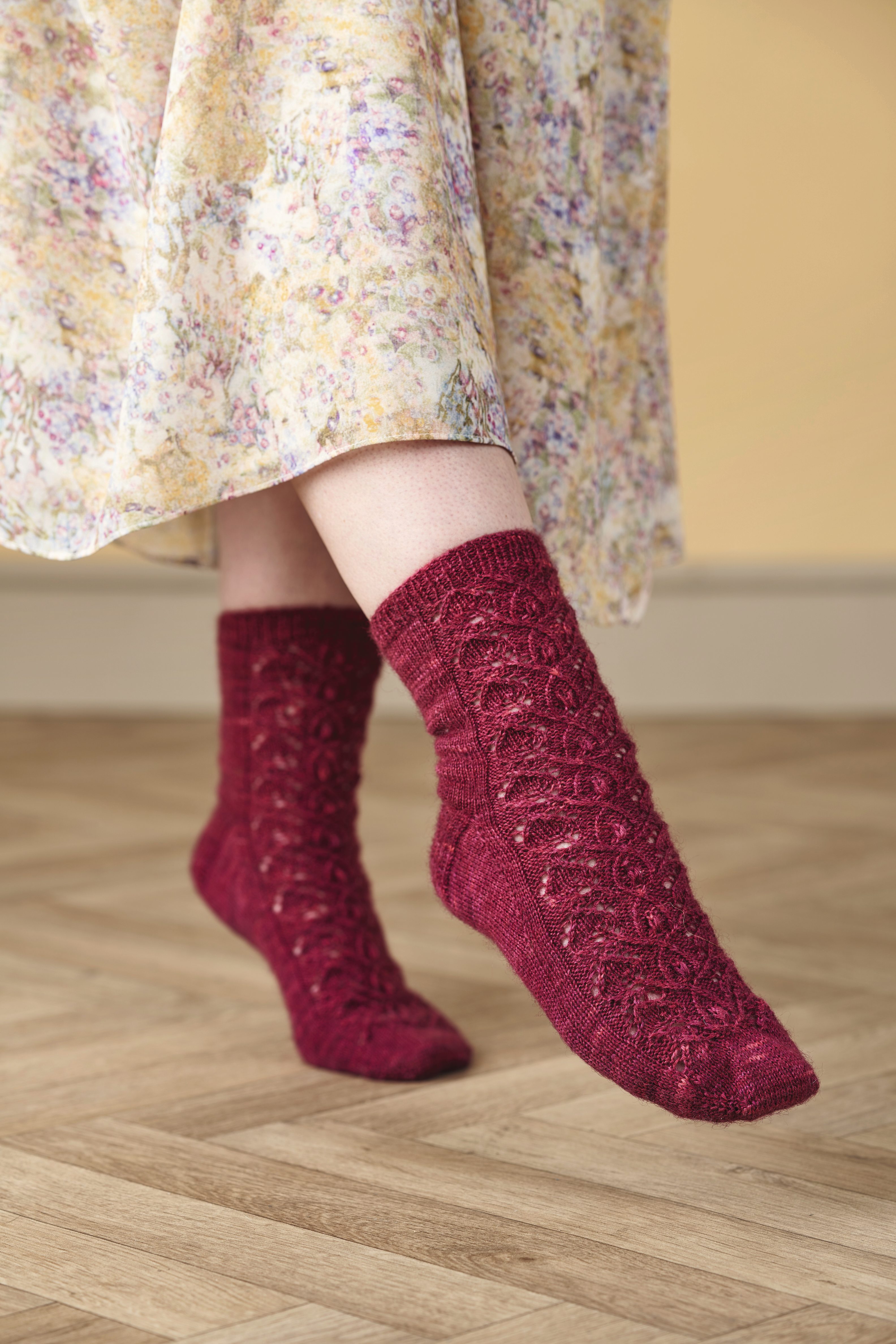 Handgefertigte rote Socken mit filigranem Muster und florales Kleid. Modisches Accessoire.