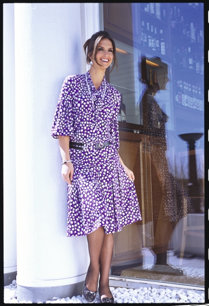 Lila Kleid mit weißem Punktmuster, fließender Schnitt, modisch, individuell mit breitem Gürtel betont.