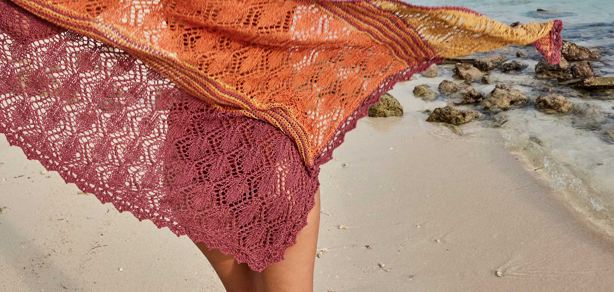 Modisches, handgestricktes Tuch in Orange und Bordeaux, filigranes Muster, ideal für den Strand.