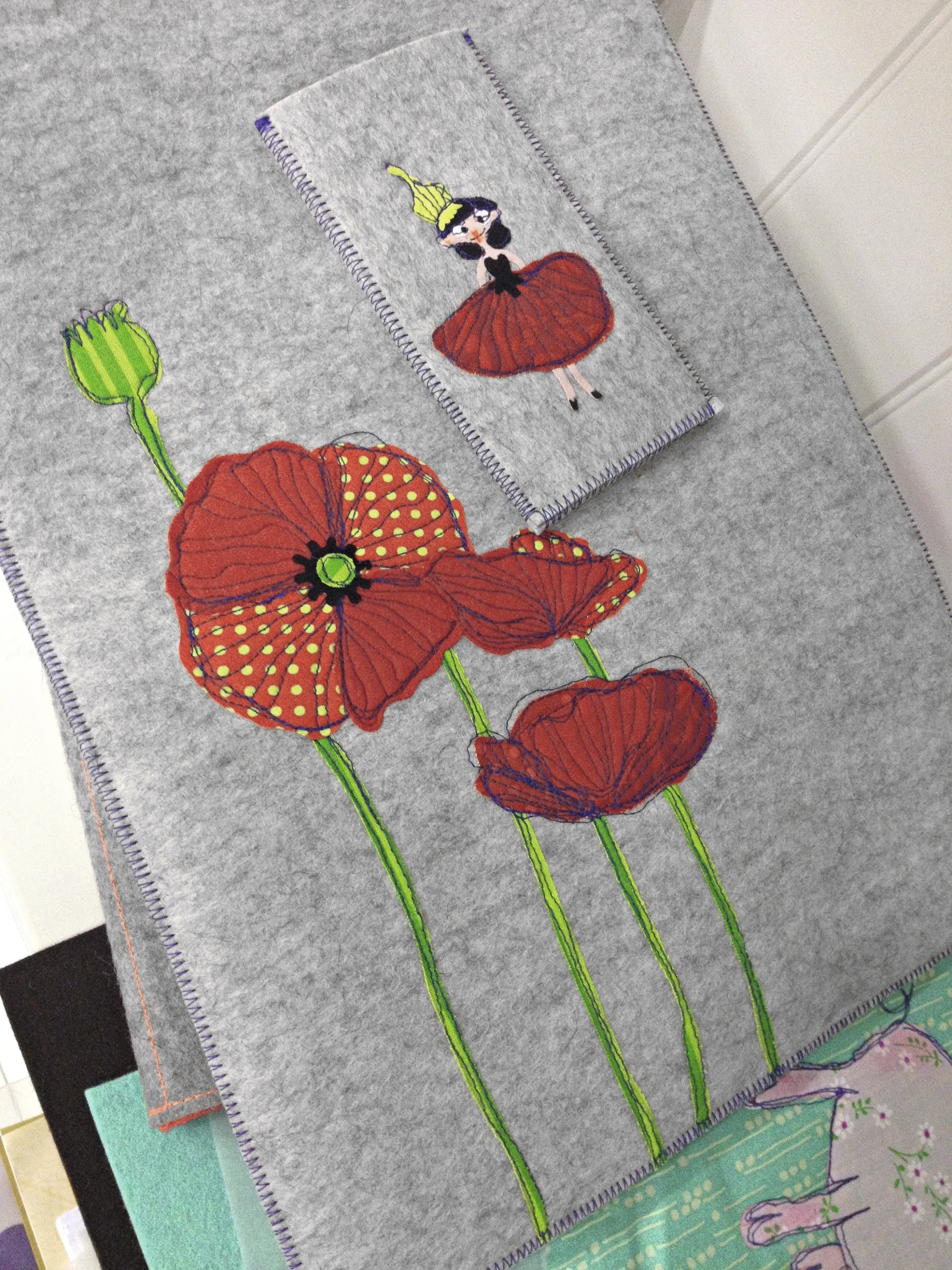 Grauer Stoff mit rotem Mohnblumenmuster und stilisierter Figur, handgemacht, kreativ, modisch.