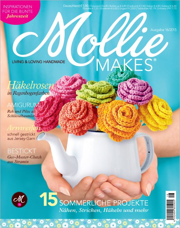 Kreativ gestaltete Häkelrosen in leuchtenden Regenbogenfarben auf einem Kännchen. Modisch, handgemacht, auffällig.