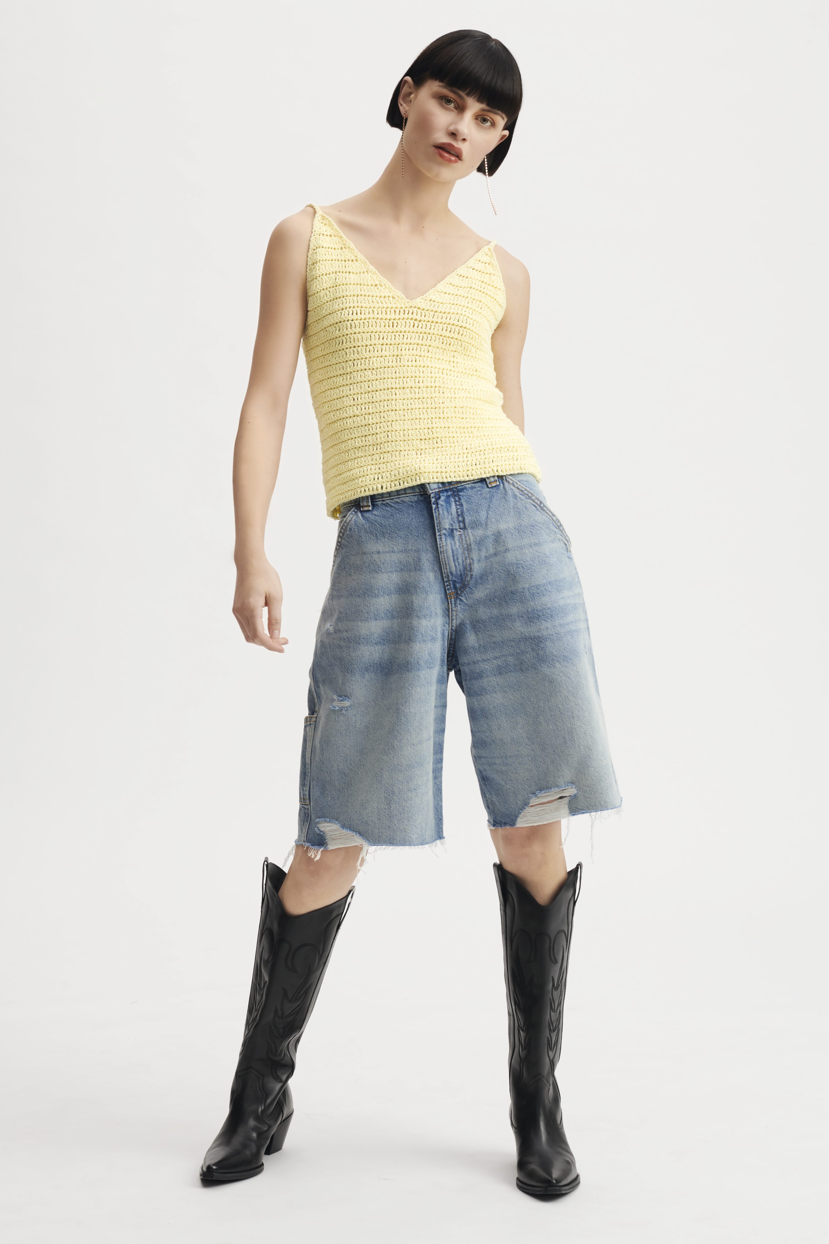 Gelbes DIY-Stricktop, blaue Jeans-Shorts mit Used-Look, schwarze Stiefel.