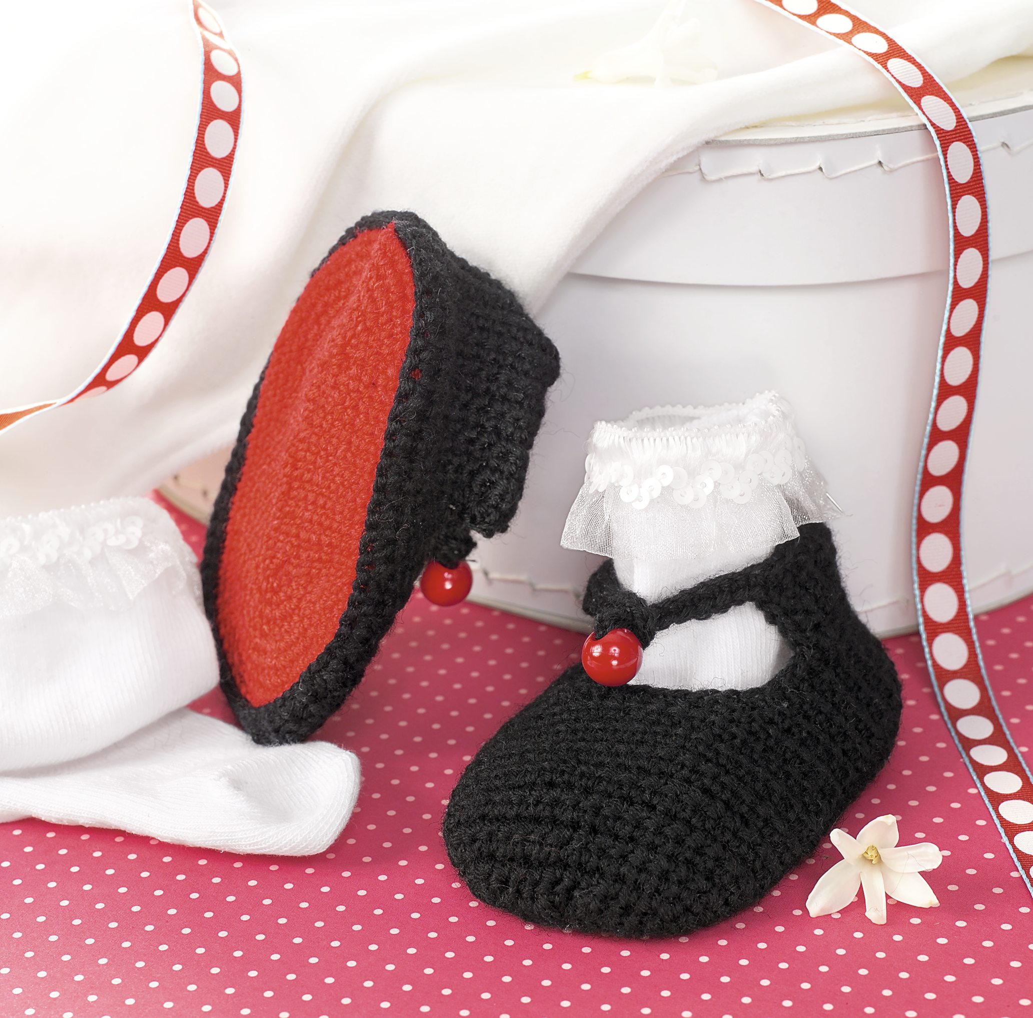 Schwarze gehäkelte Babyschuhe mit roter Sohle, Spitze und Perlen. Modisch und handgemacht.