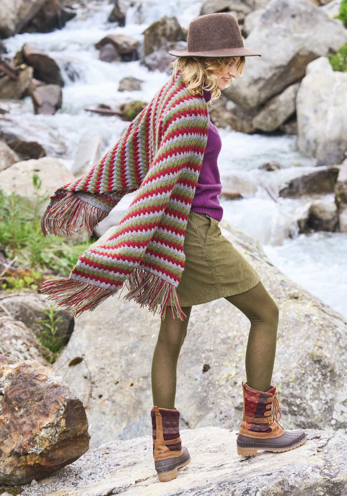 Bunter Poncho, Streifenmuster, handgemacht; lila Pullover, olivgrüner Rock, robuste Boots. Modisch, DIY.