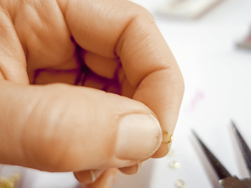 Nahaufnahme einer Hand, die filigranen, handgemachten Schmuck erstellt. Fokus auf eleganter Handarbeit.