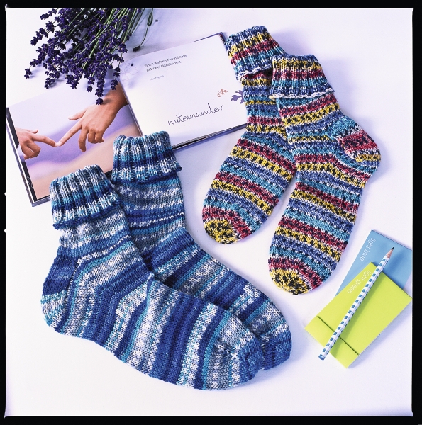 Farbenfrohe, selbstgemachte Socken; gestreiftes, handgestricktes Design in Blau- und Rotnuancen.