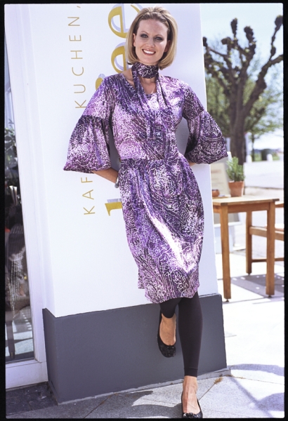 Fließendes Kleid in Violett mit Muster, Glockenärmel, Gürtel; kombiniert mit Leggings und Ballarinas.