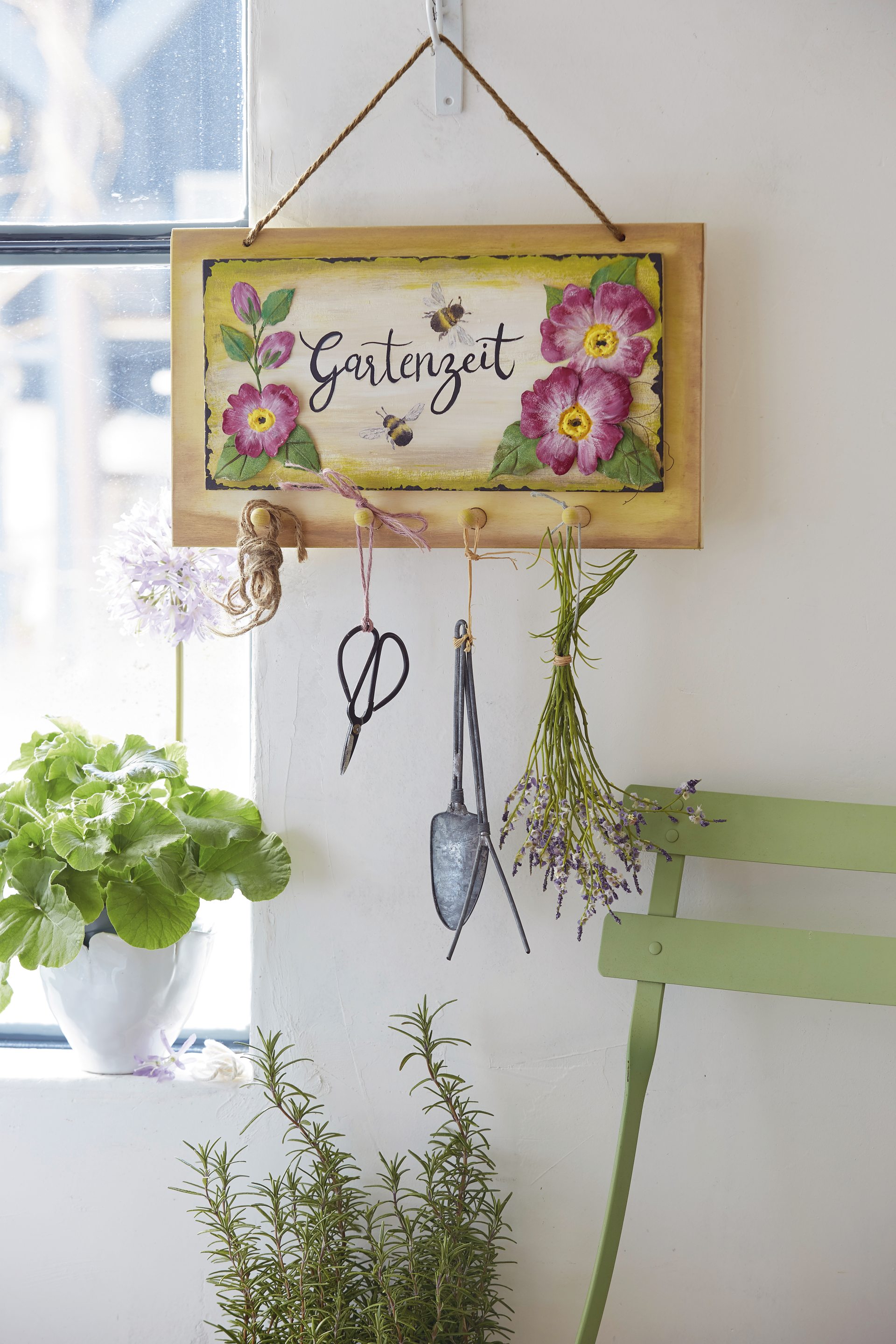 Holzschild mit Blumenmotiv, handgemaltet, ergänzt durch Gartenschere und Lavendelbüschel. DIY-Charme.