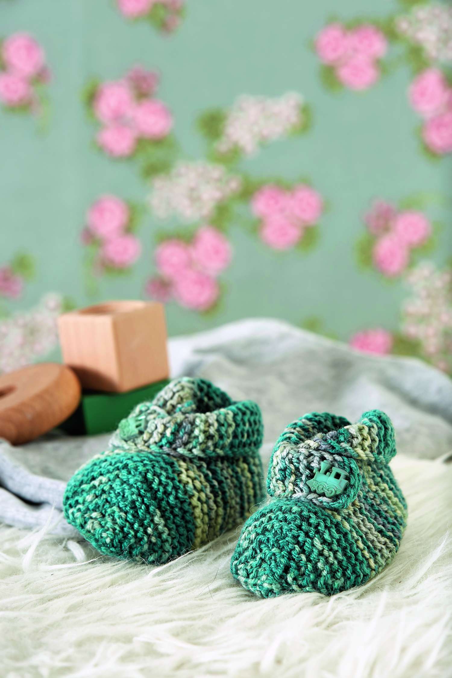 Grüne, gestrickte Babyschuhe mit Knopfverschluss, handgemacht, modisch, mit farbigen Streifen und weichem Material.