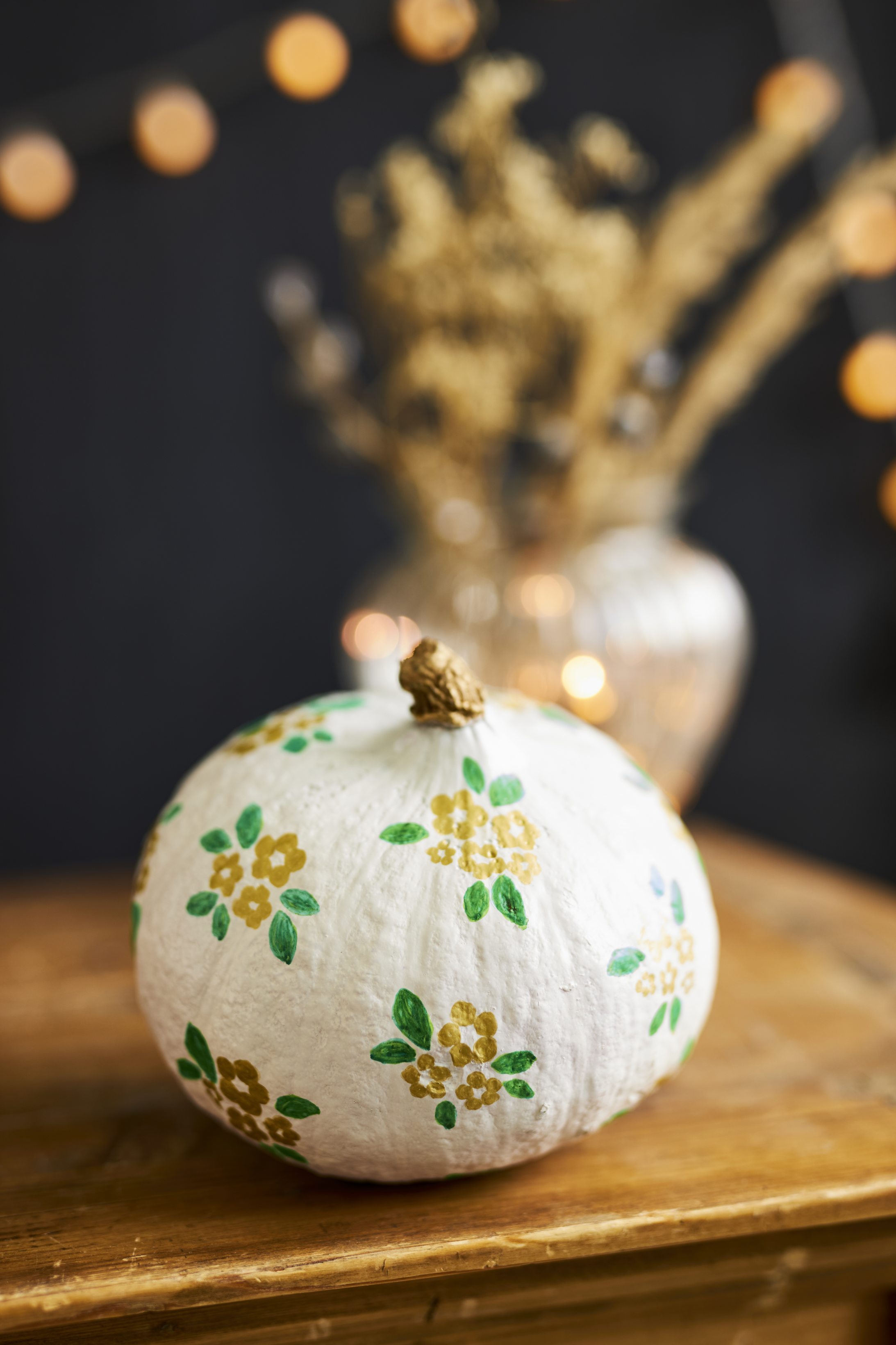 Weißer Kürbis, handbemalt mit gelben Blumen und grünen Blättern; kreativ, DIY, handgemacht.