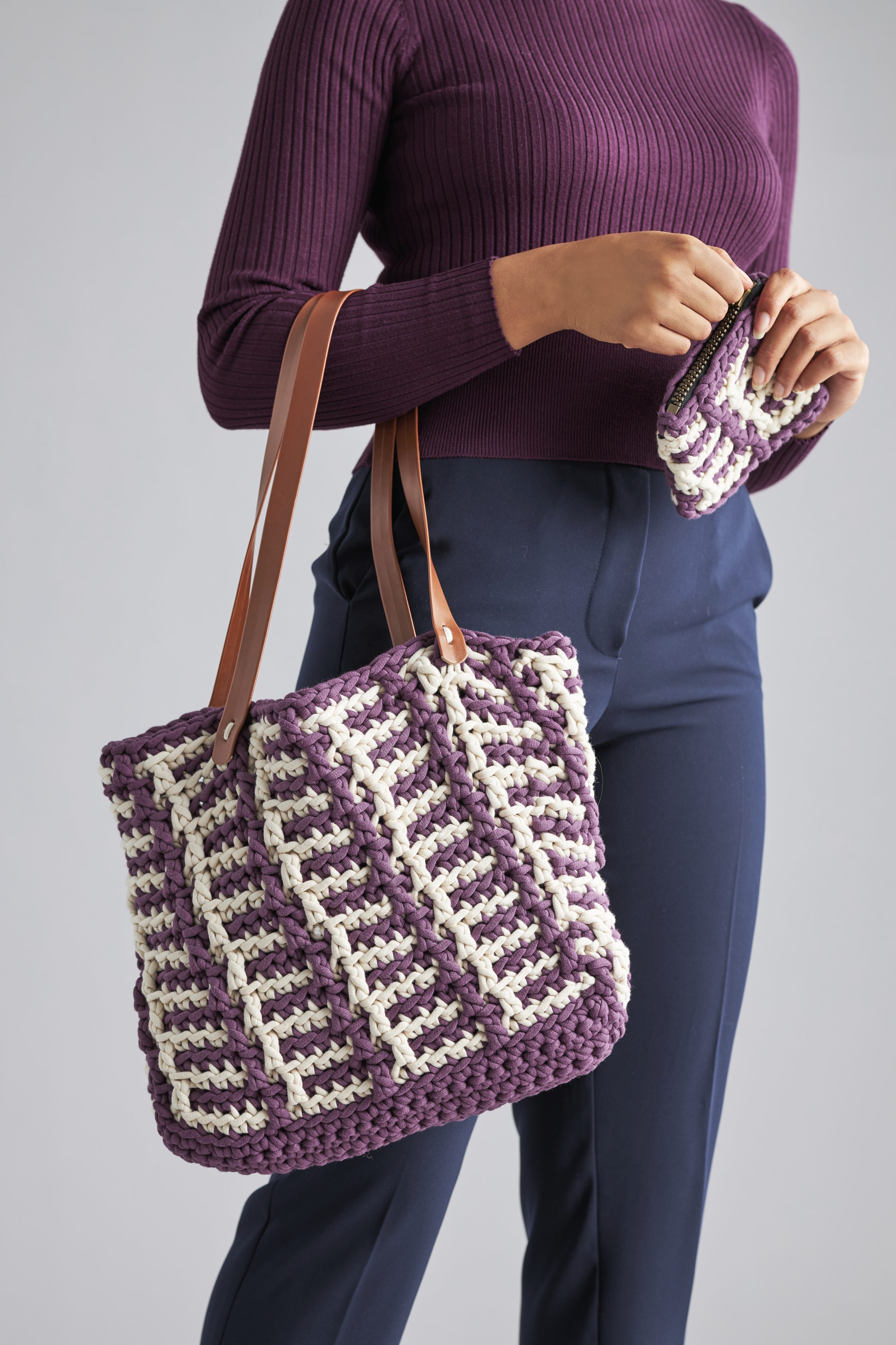 Handgemachte Tasche und Portemonnaie in Lila und Weiß, grob gehäkelt, mit braunen Ledergriffen, modisch.