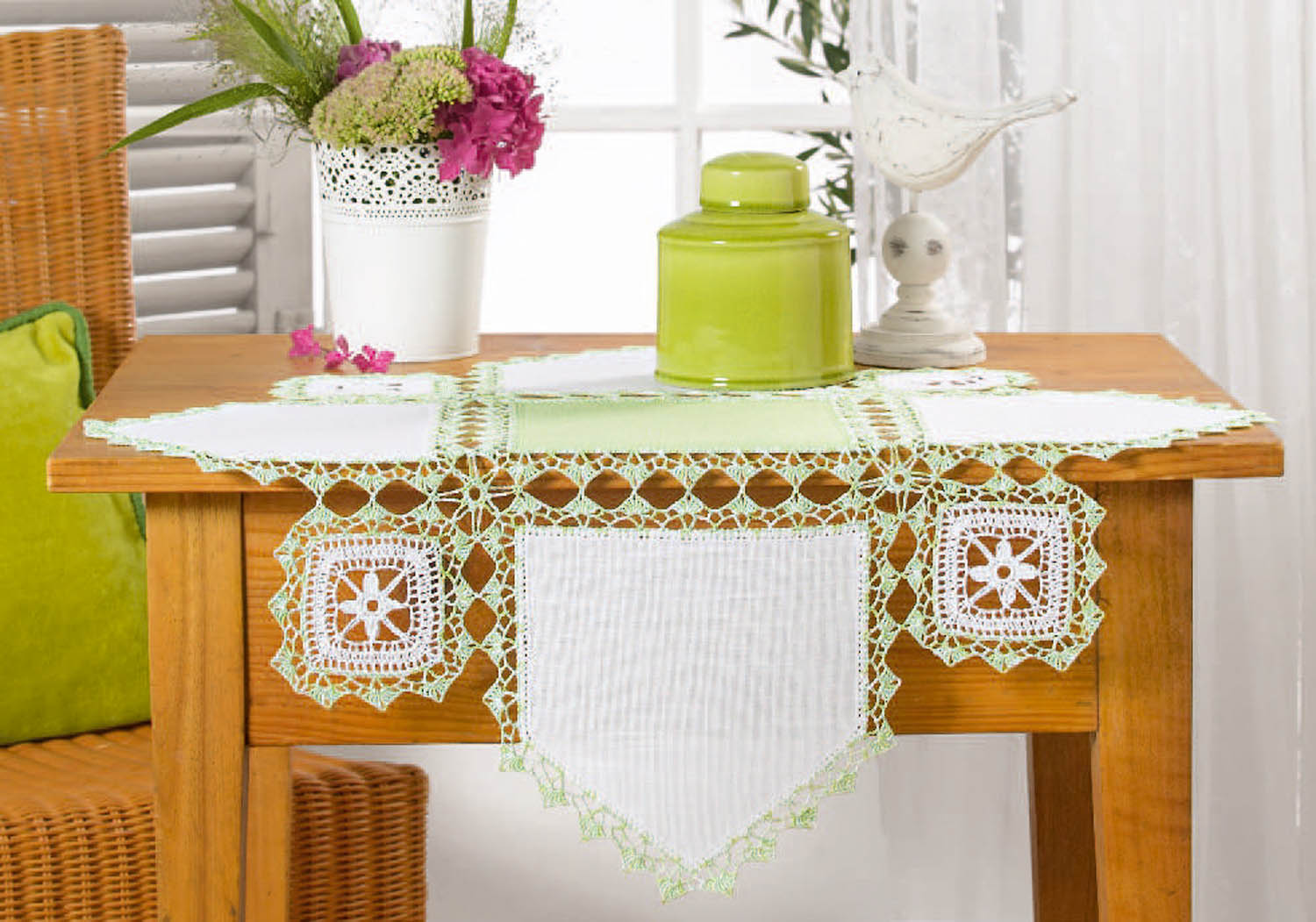 Weiß-grüne Tischdecke mit gehäkeltem Muster. Modische, handgemachte Details und geometrische Formen.