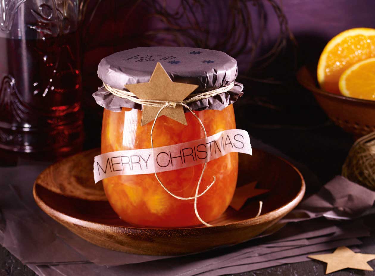 DIY-Glas mit Marmelade, dekoriert mit festlichem Papier, Sternmotiven und 'Merry Christmas' Schriftzug.