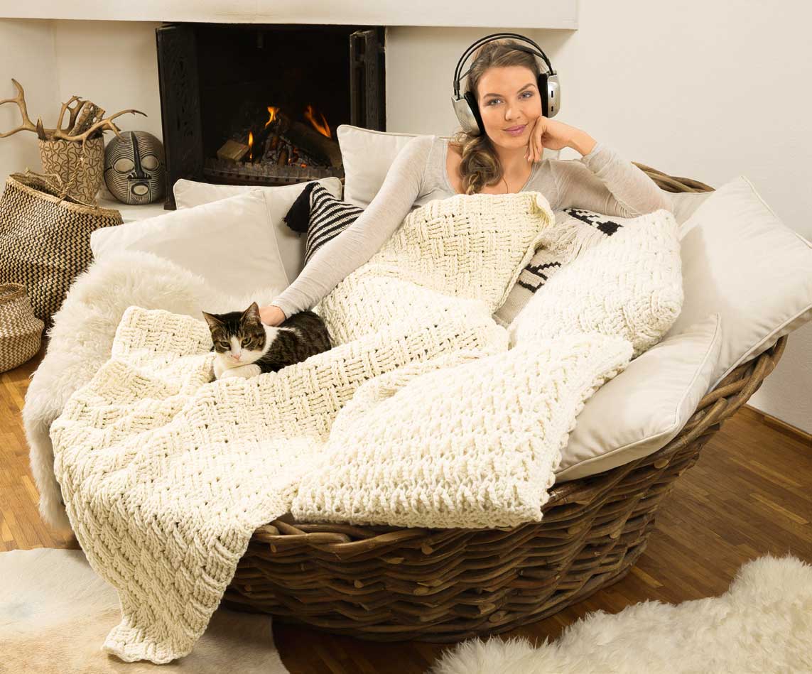 Cremefarbene, handgemachte Decken mit grobem Strickmuster. Bequemes, lässiges Outfit: modisch und heimelig.