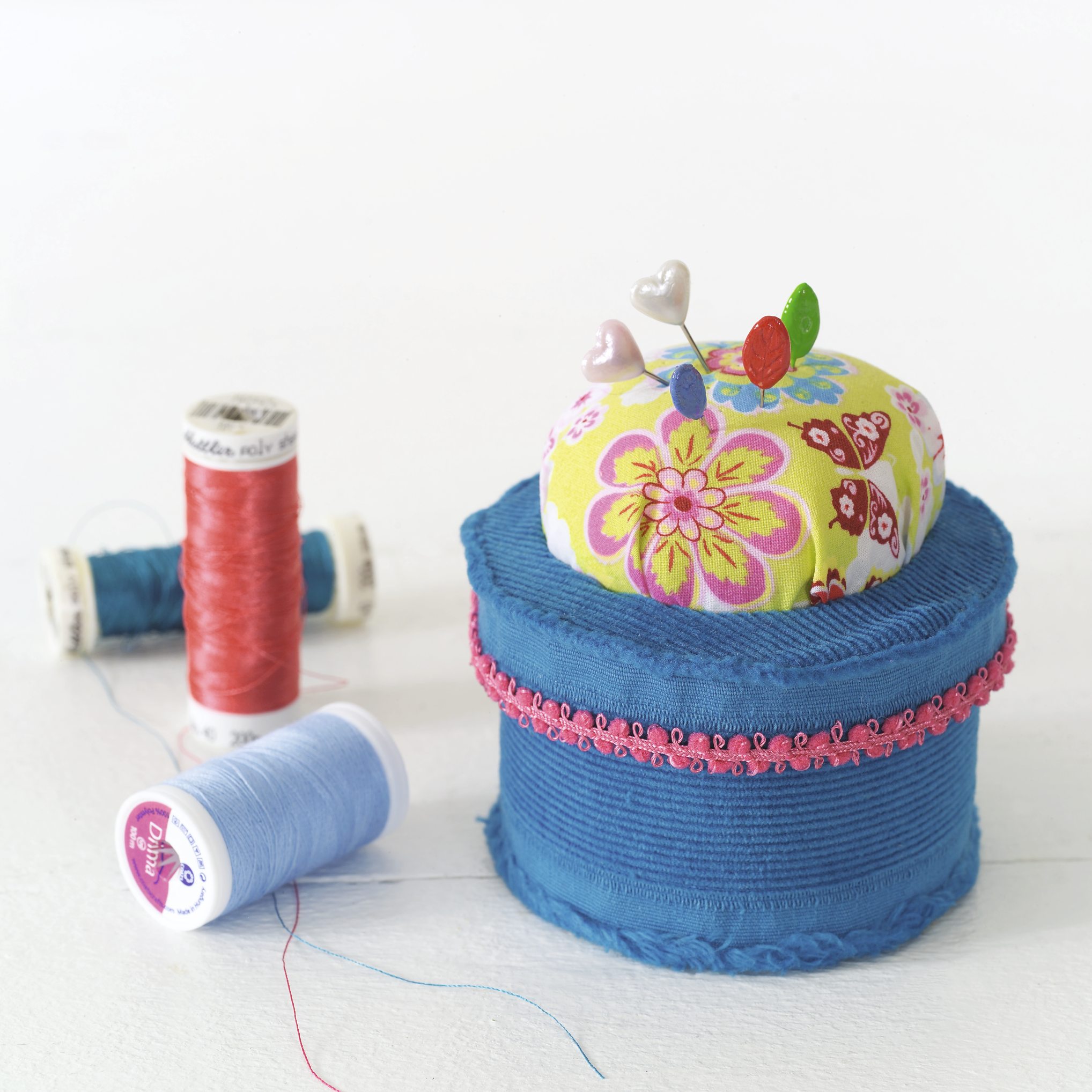 Handgemachtes Nadelkissen: bunte Blumenmuster, blaue Basis, rosa Spitze. Modisch und kreativ.