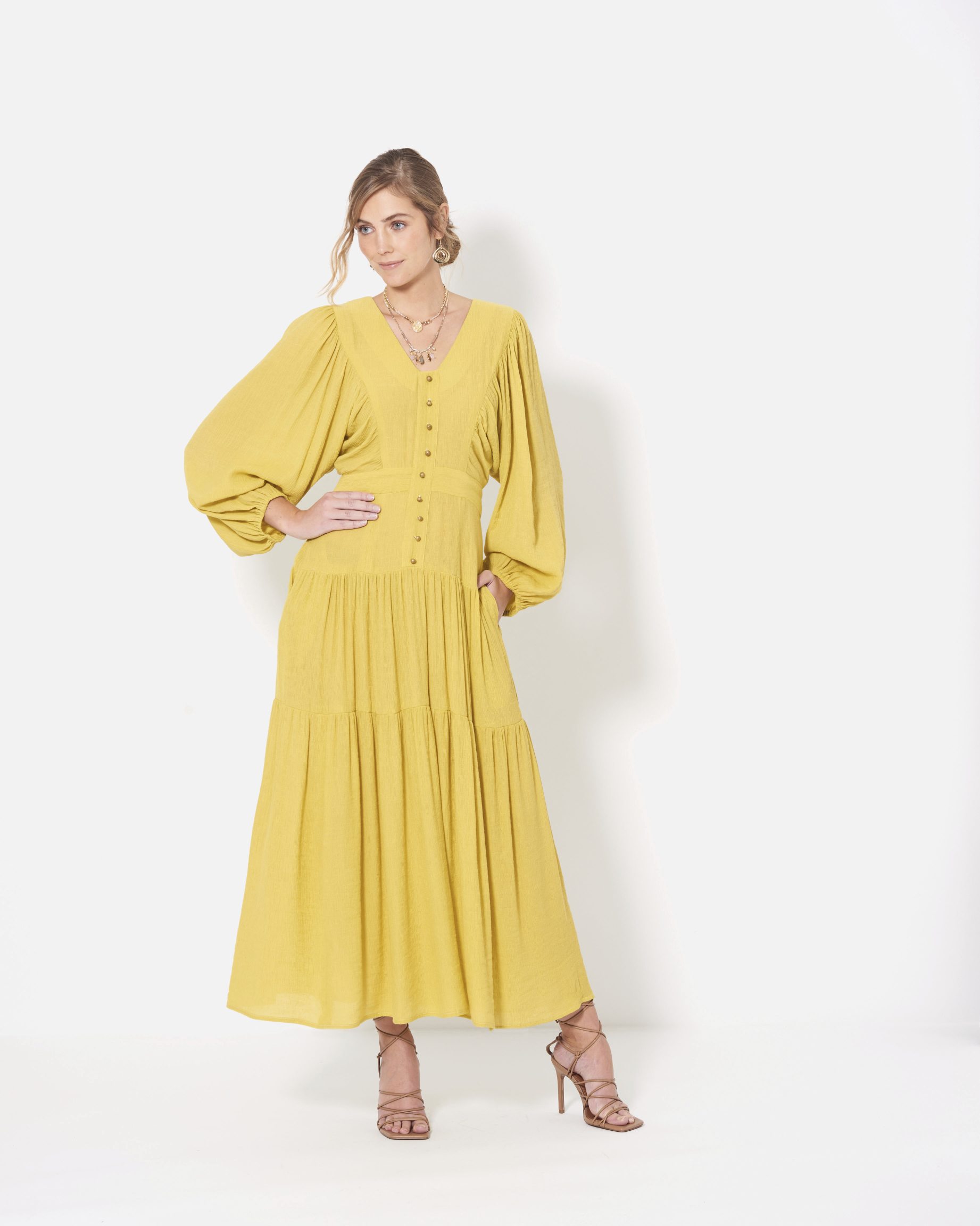 Modisches, langes gelbes Kleid mit voluminösen Ärmeln und Knopfleiste, elegant und stilvoll.