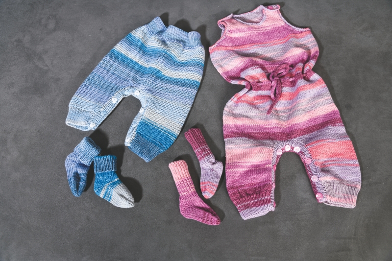 Handgemachte Strampler in Blau und Rosa mit Farbverlaufsmuster. Modische, gestrickte Socken als Ergänzung.