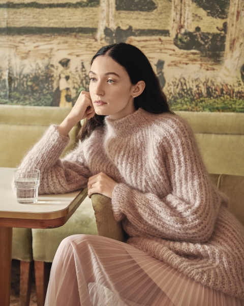Flauschiger Strickpullover in zartem Rosa, kombiniert mit fließendem Plisseerock, modisch und gemütlich.