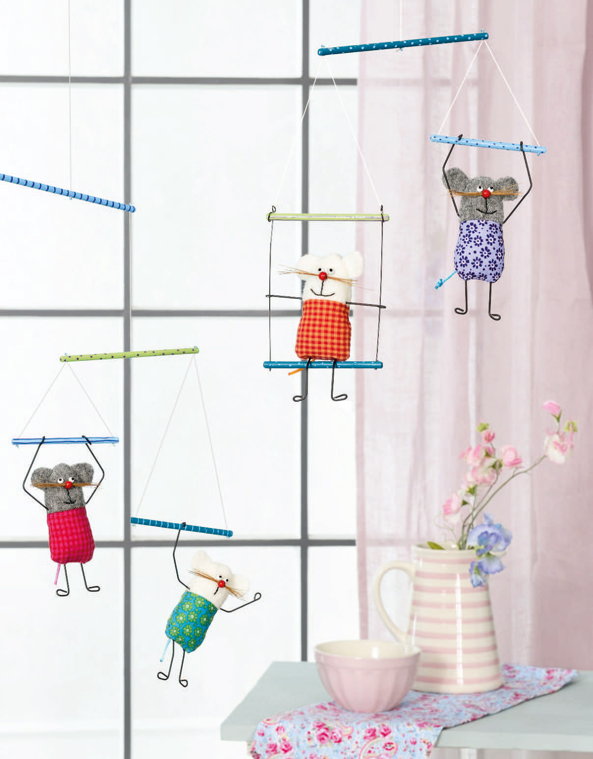 Selbstgemachte Mäuse im farbenfrohen Karomuster, mit schwingenden Armen an bunten Stäbchen. Handarbeit & DIY-Charme.