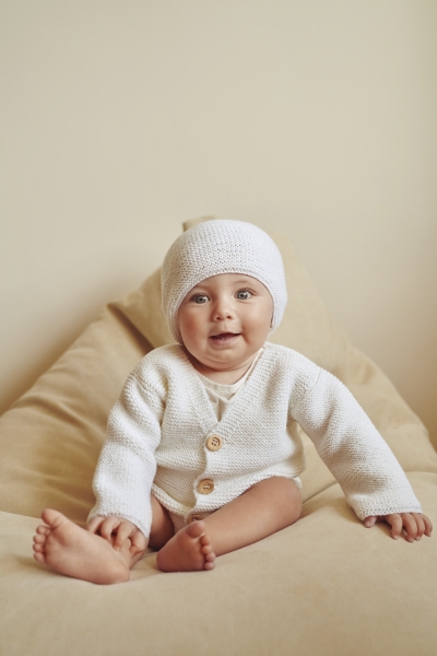 Weißer Strickanzug mit Holzknöpfen, modisch und selbstgemacht. Weiches, gemustertes Design für zarte Haut.