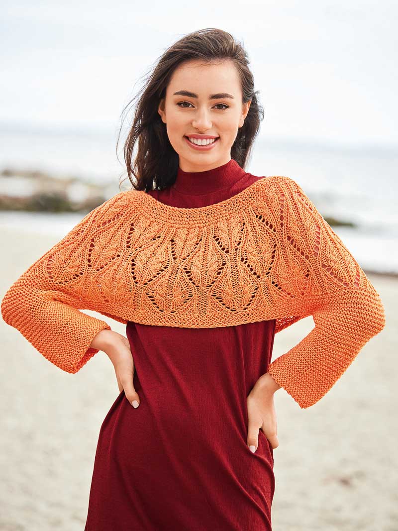 Oranger Strick-Bolero im Blättermuster, über rotem Kleid. Modisch, handgemacht, DIY-Charme.