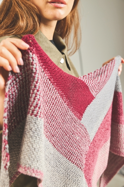 Modischer, handgestrickter Schal in Rot-, Grau- und Rosatönen mit einem auffälligen, geometrischen Muster.