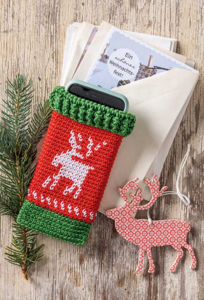 Rote, gestrickte Handyhülle mit Rentiermuster, grünem Rand; modisch, DIY, festlich.