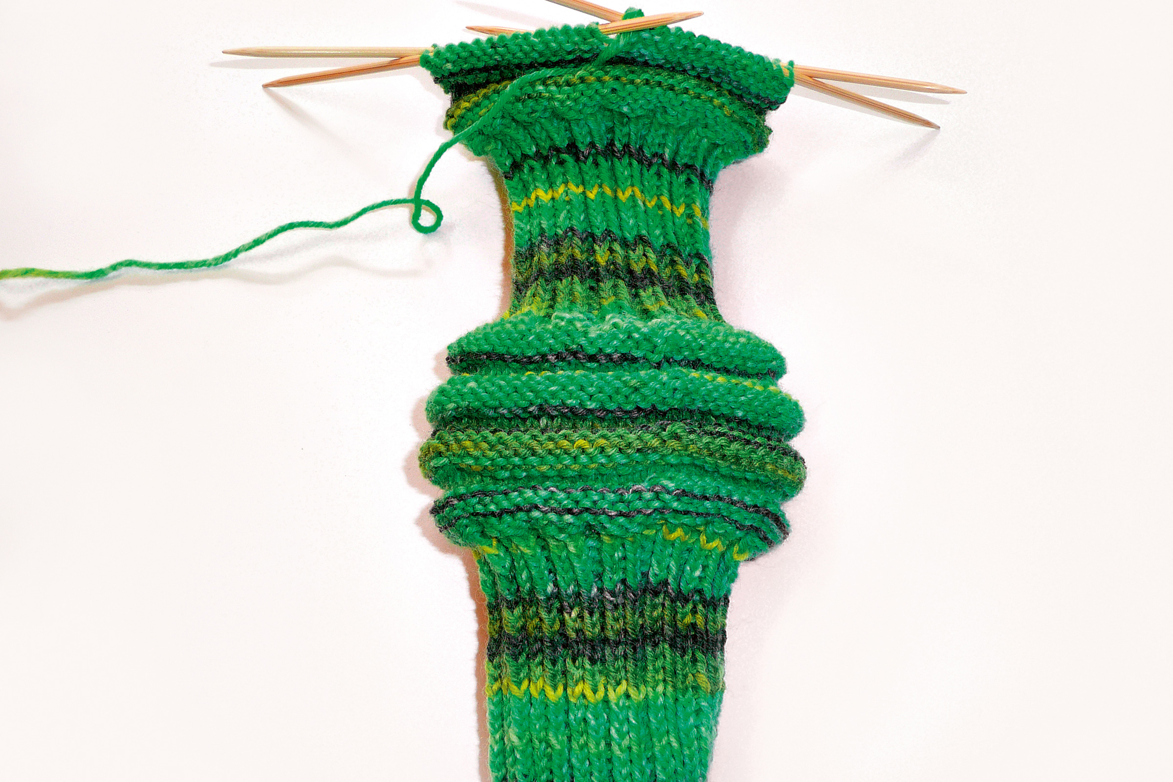 Selbstgemachte Socke in Grün, Muster mit Farbverlauf. Modisch, handarbeit, kreativ.