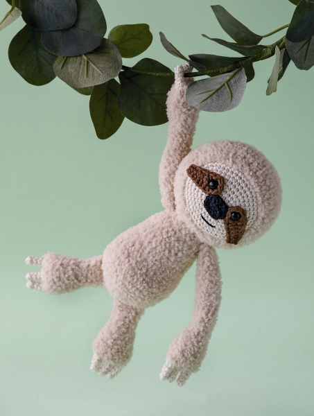 Handgemachtes Faultier aus beigem Garn, flauschig, mit maskiertem Gesicht. Modisch, DIY.