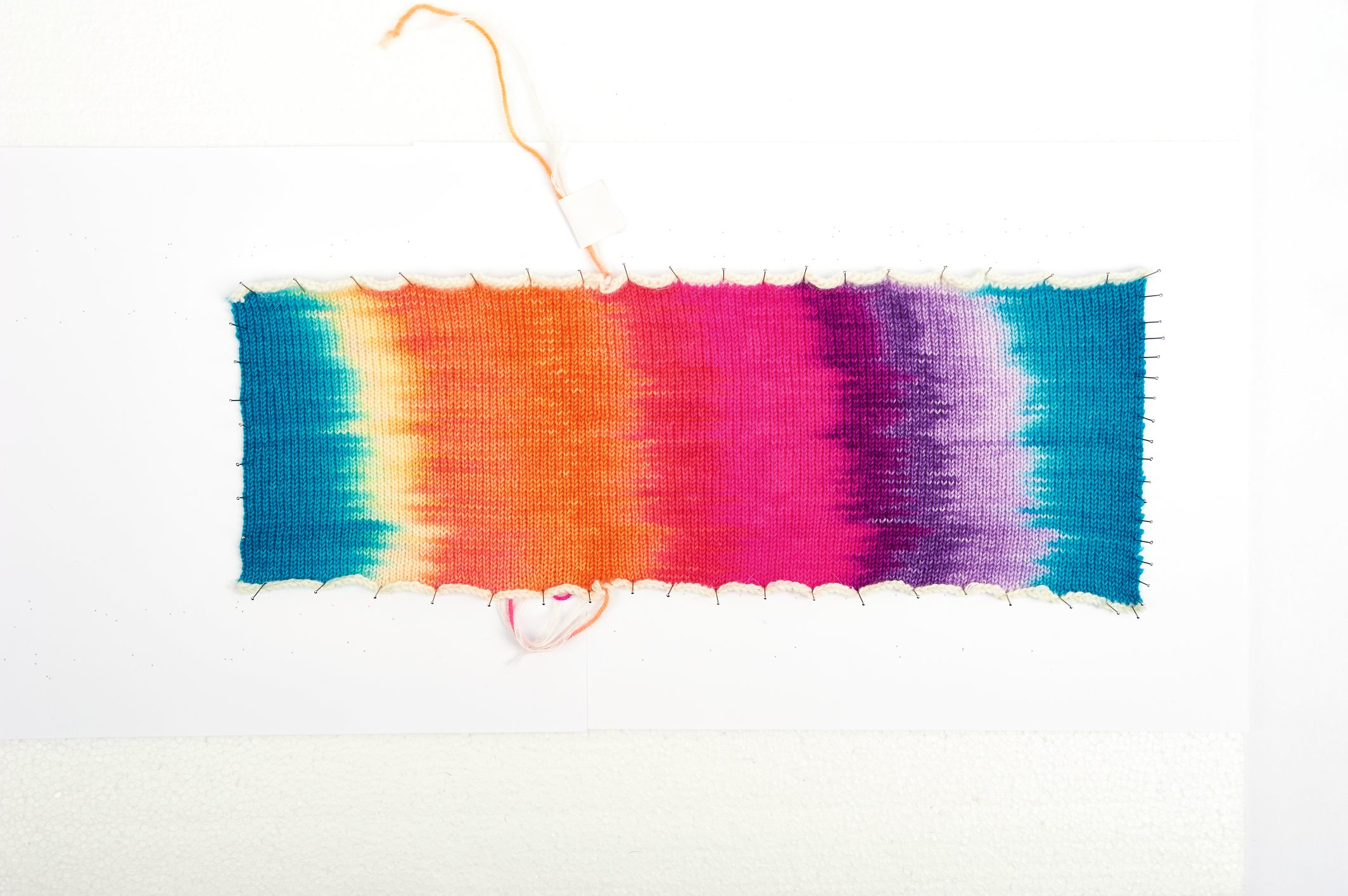 Modisches handgemachtes Stoffmuster mit lebendigem Farbverlauf in Orange, Pink, Violett und Blau.