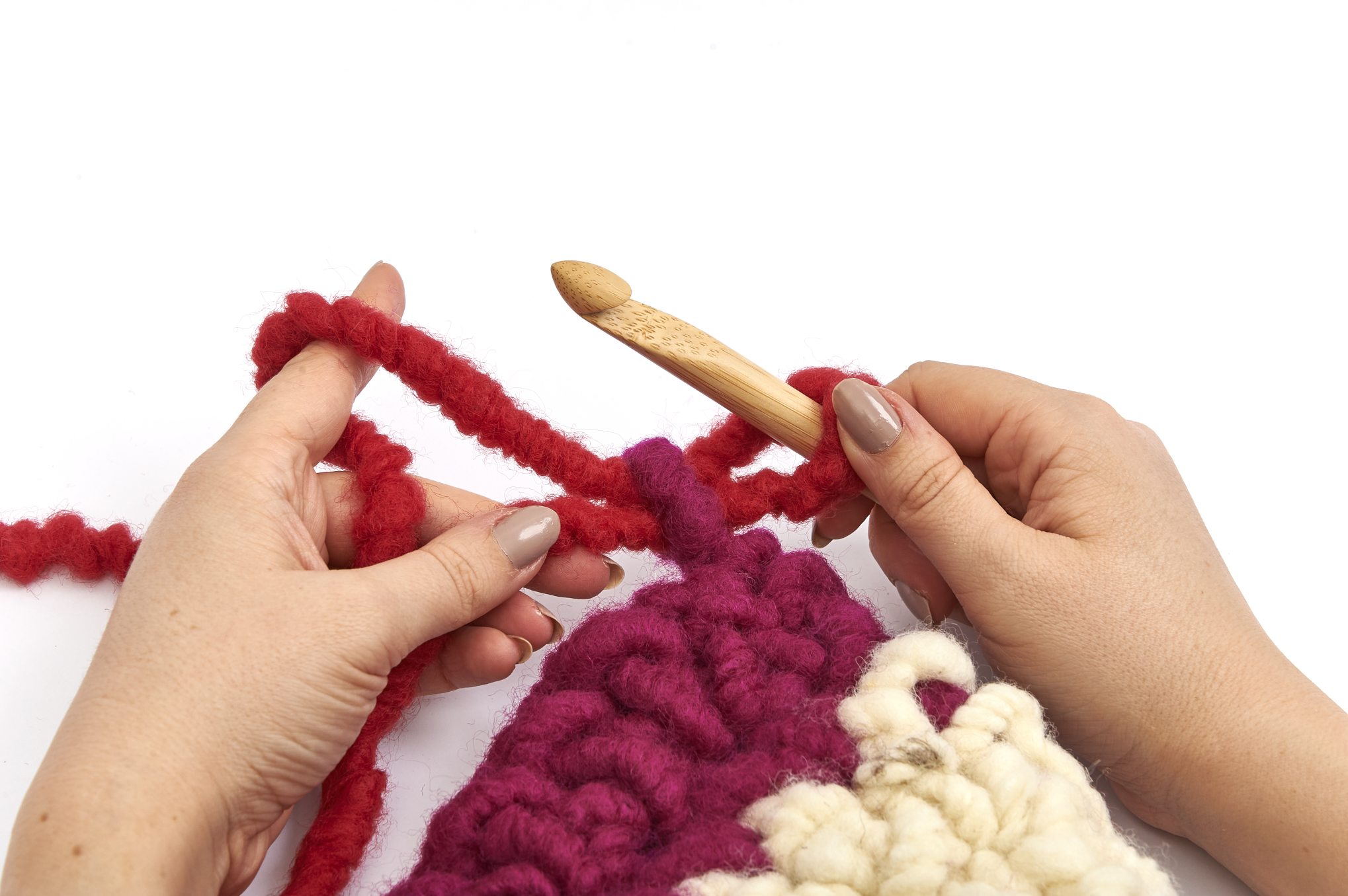 Handarbeit: dicke, rote und cremefarbene Fäden, grobes Muster, große Nadel. DIY-Charme, modisch und kreativ.