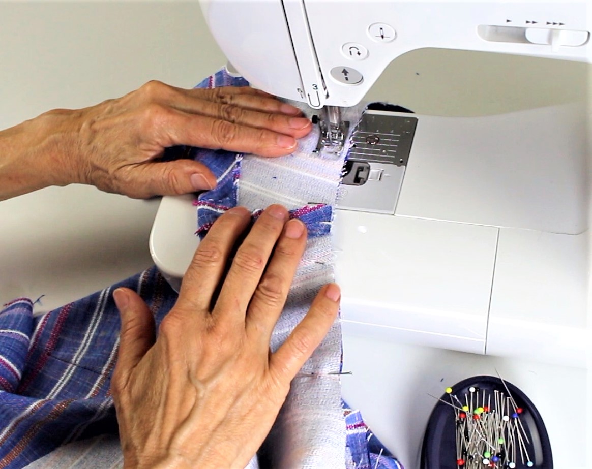 Blau gestreifter Stoff, handgemacht und modisch, wird auf einer Nähmaschine verarbeitet.