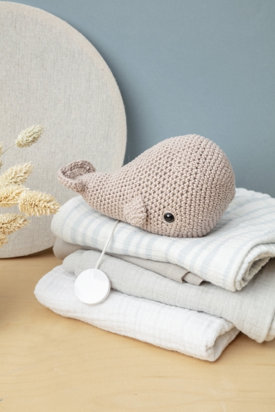Gehäkelter Wal in Beige, zarte Texturen, stilvoll auf weichen Decken platziert. DIY, handgenäht.