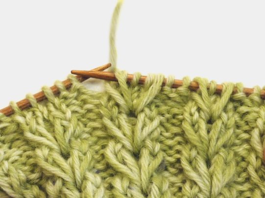 Grünes, handgemachtes Strickmuster mit Zopfmuster. Lebhafte Farbtöne, DIY-Charme, texturiert und stilvoll.