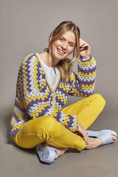 Modischer, handgemachter Cardigan in Gelb, Lila und Weiß, kombiniert mit gelben Hosen. DIY-Chic.