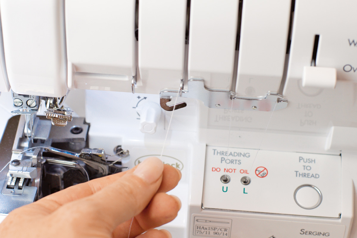 Person arbeitet an einer Overlockmaschine; selbstgemacht, handarbeit, detailreich.