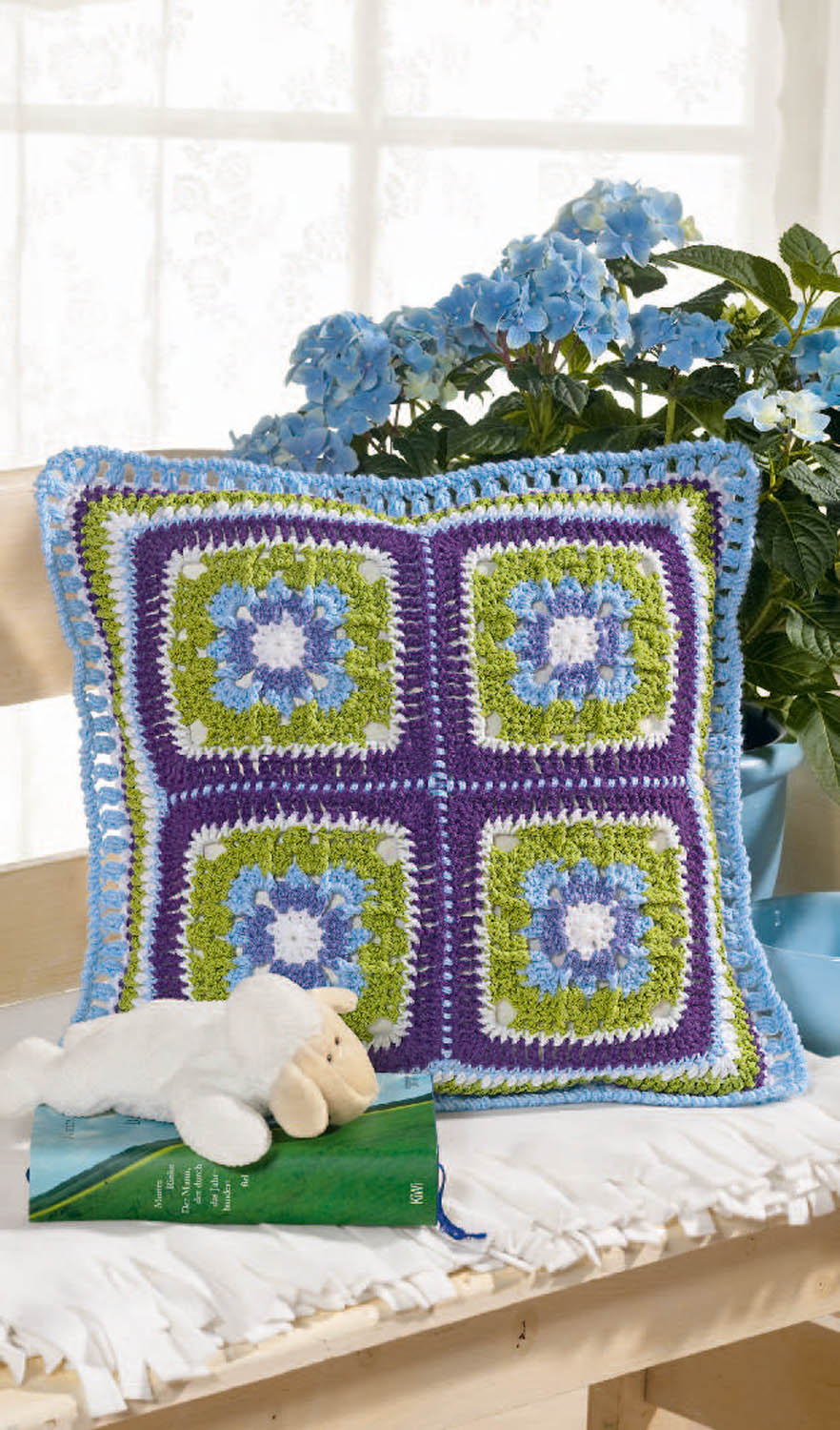 Modisches Kissen, gehäkelt mit buntem Muster aus Lila, Blau und Grün. DIY, handgearbeitet, rechteckig, Boho-Stil.