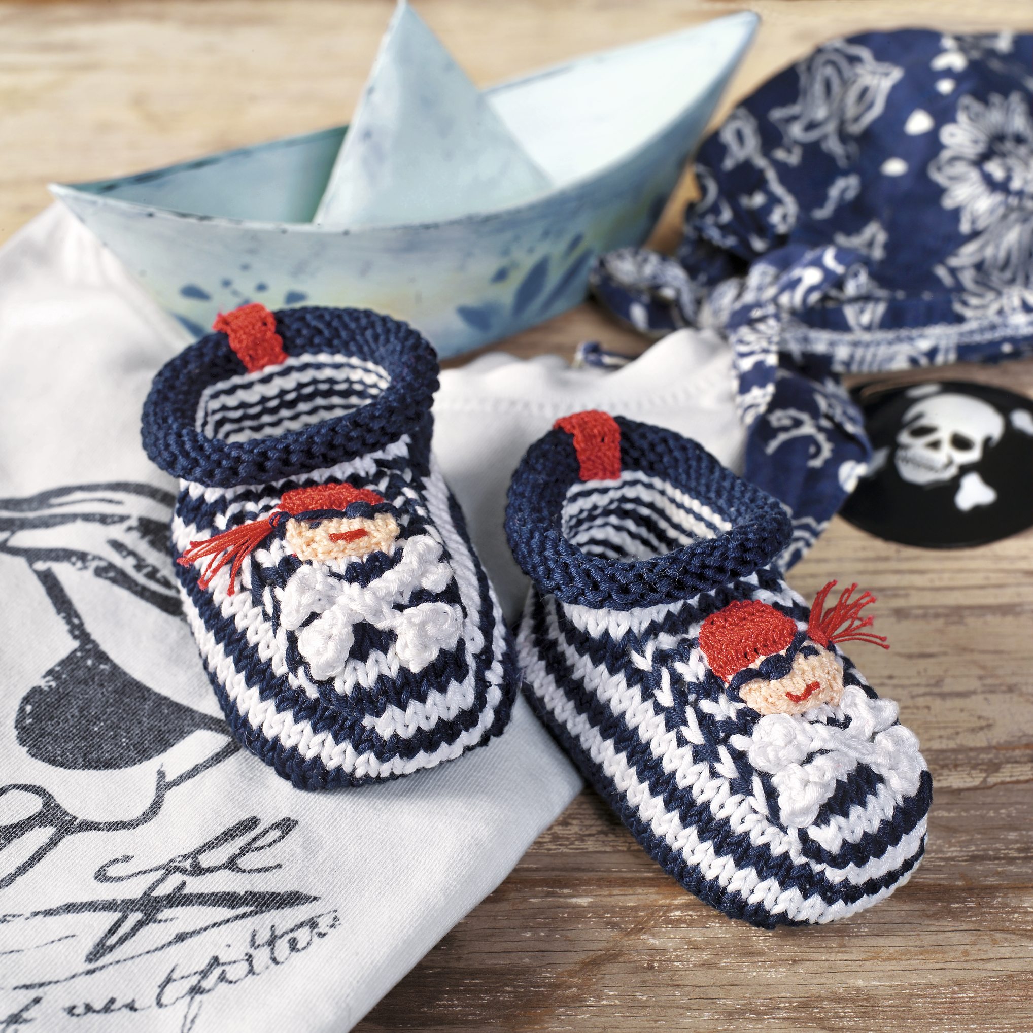 Gestreifte, handgemachte Babyschuhe in Blau-Weiß mit Matrosenmotiv und roten Details. Modische und kreative Handarbeit.