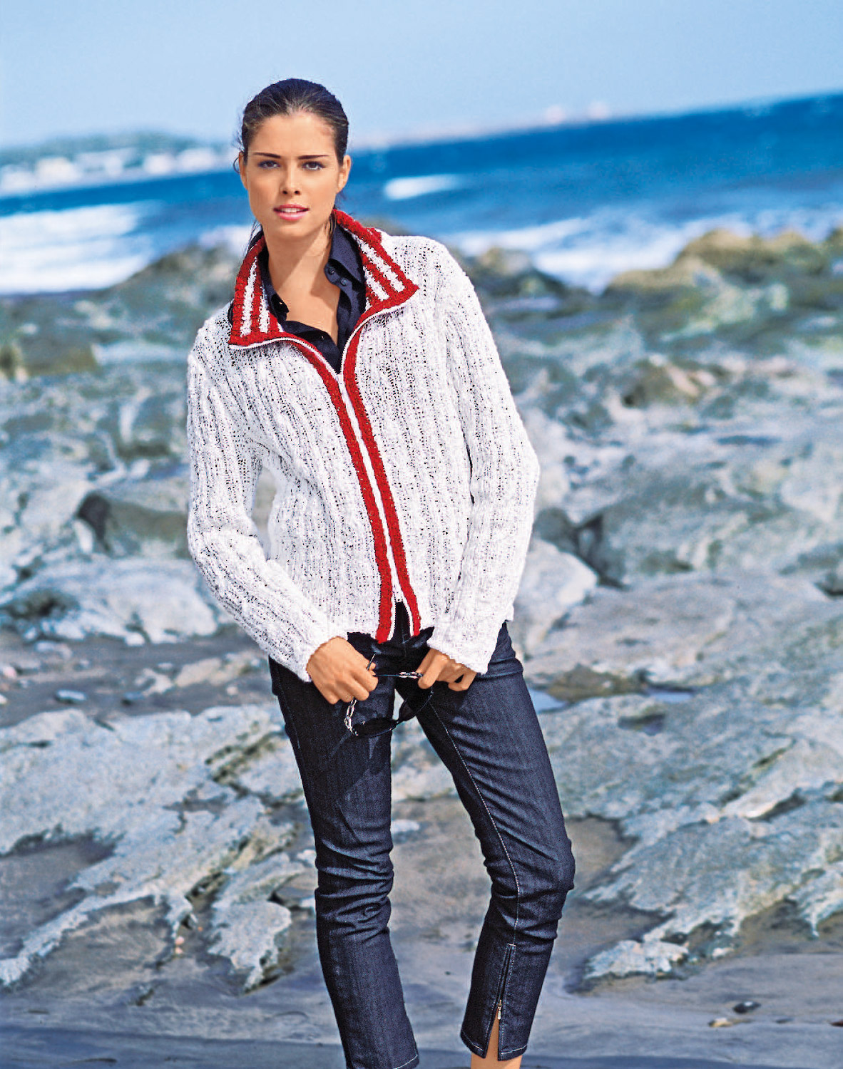 Weiße Strickjacke mit roten Akzenten, modischer Schnitt, kombiniert mit dunkler Jeans. DIY-Vibes.